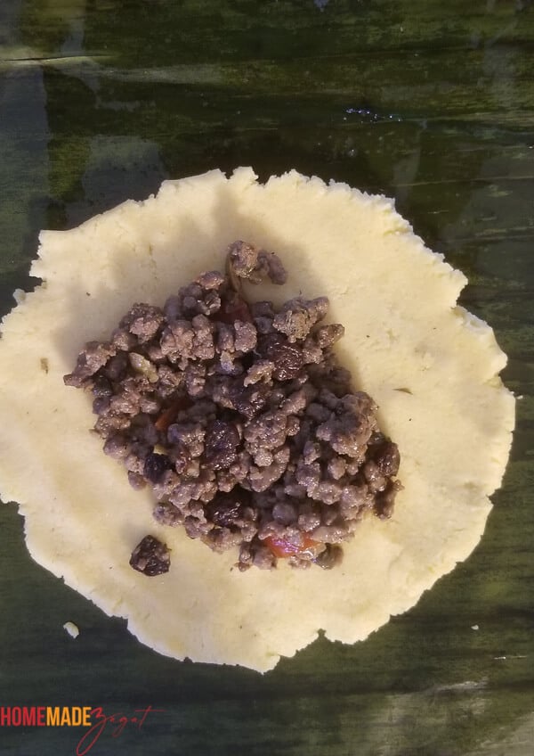 Open dough of pastelle on a banana leaf with meat filling