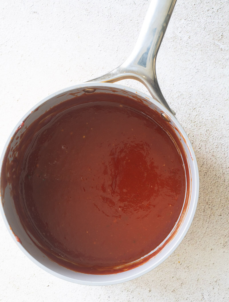 The sauce fully simmered down and combined together in a sauce pot on a white counter top.