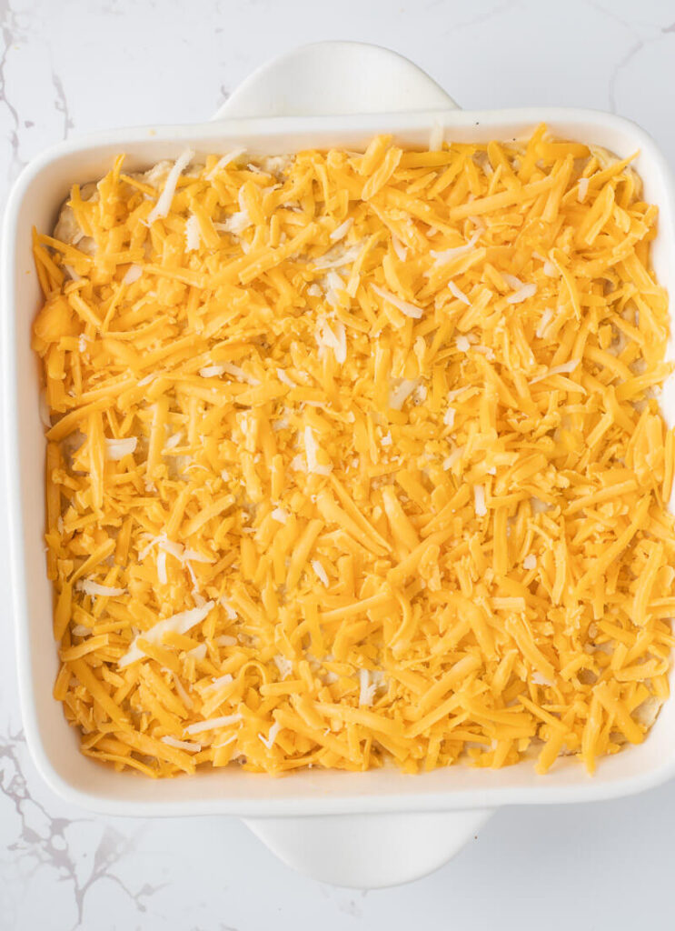 Green banana mixture in a greased baking dish, covered with cheese.