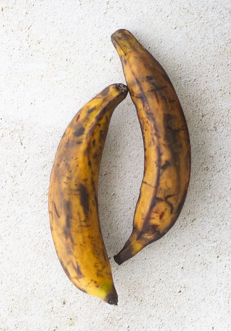 A picture of two yellow ripe plantains with black spots.