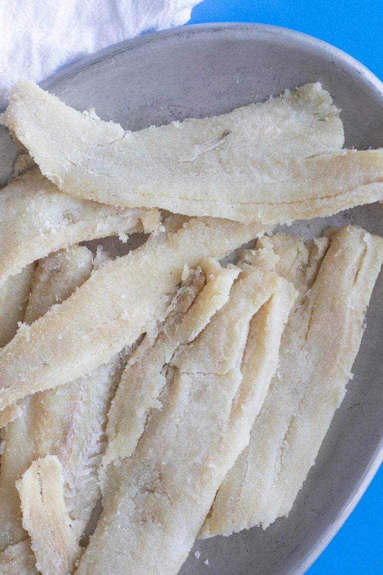 Salted cod on a silver plate on a blue background with a white napkin.