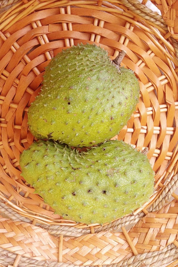 Picture of a soursop fruit on a brown basket.