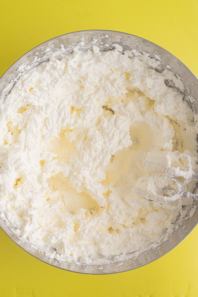 Heavy cream mixed to stiff peaks in a large metal bowl.