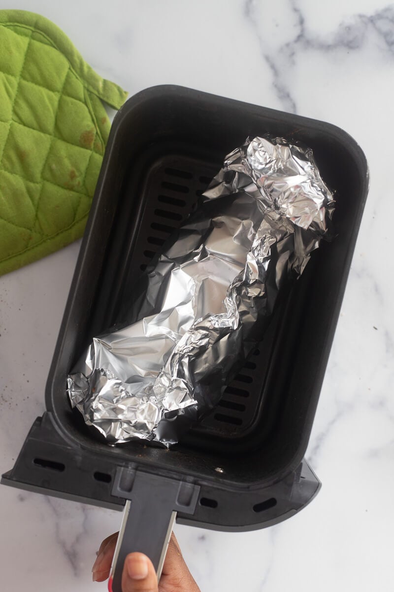 Fish wrapped in foil and placed in the tray of the air fryer.
