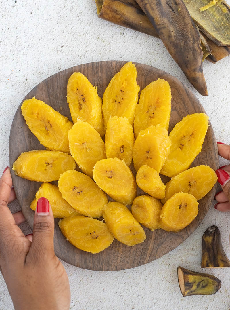 Slices of ripe boiled plantain spread out in a bowl.