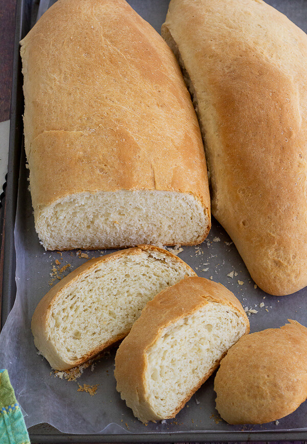 Two baked loaves of Caribbean butter bread with one sliced to show the inside.