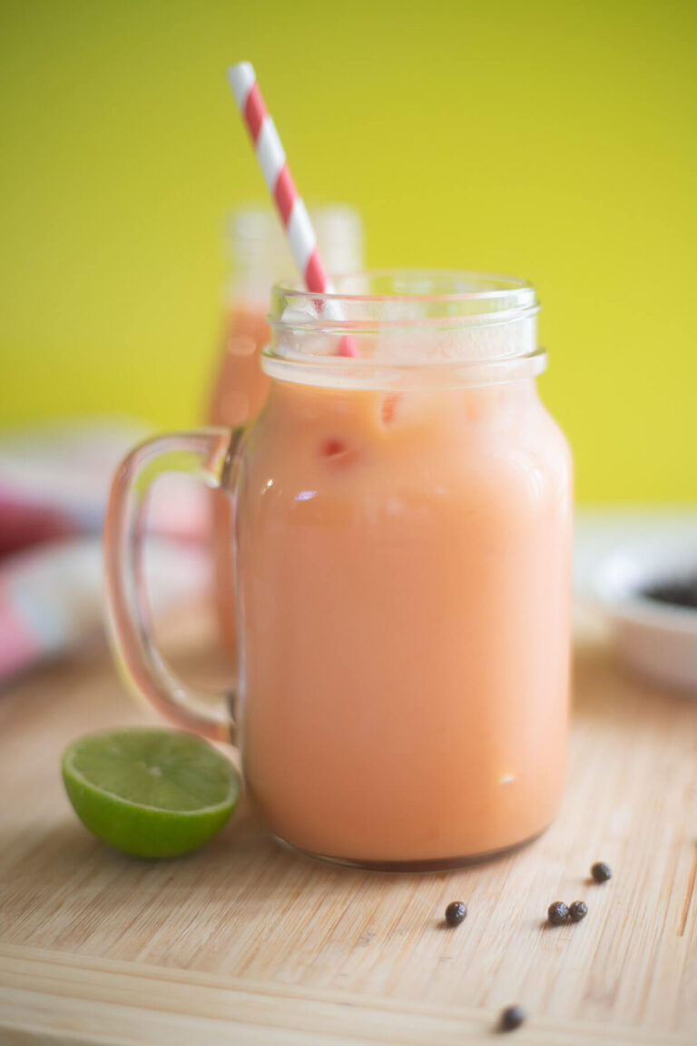 Creamy Caribbean pawpaw drink in a mason jar with a slice of lime on the side.