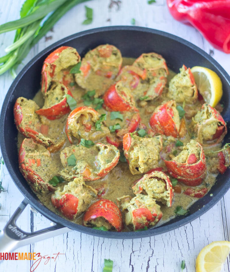 Lobster tails curried down in coconut milk in a black pot