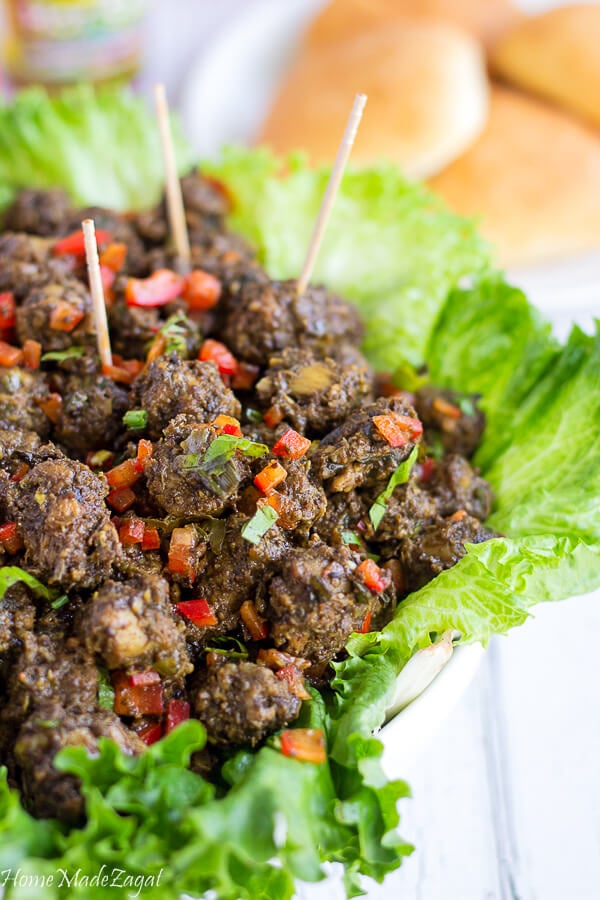 Geera chicken necck pieces cut up with toothpicks on a bed of lettuce in a white bowl.
