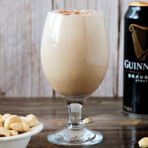 Guinness punch in a glass with a serving of peanuts.
