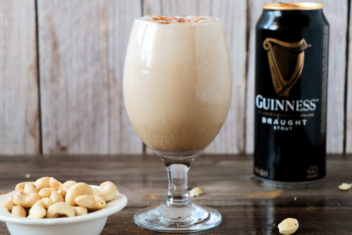 Guinness punch in a glass with a serving of peanuts.