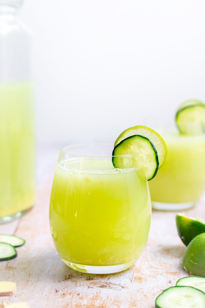 A glass of cucumber and lime juice with a garnish of lime and cucumber, perfect for hydrating on a hot summer day.