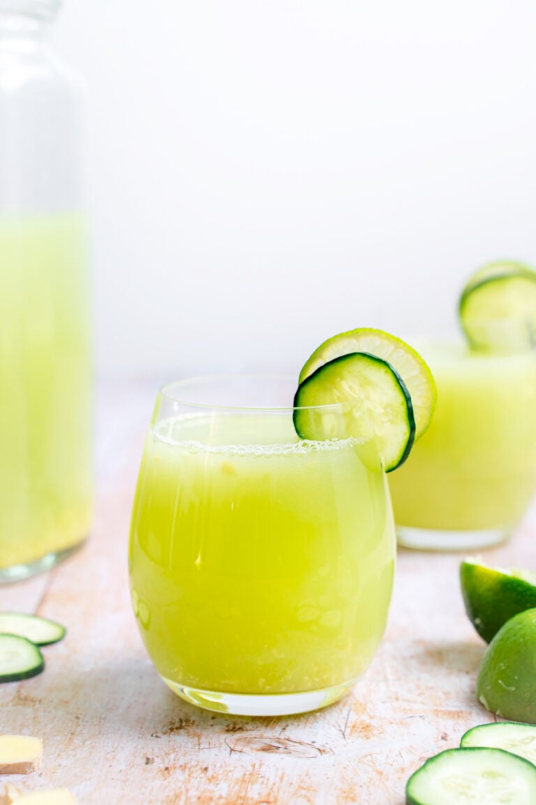 A refreshing glass of cucumber and lime juice with a garnish of lime and cucumber, perfect for hydrating on a hot summer day.