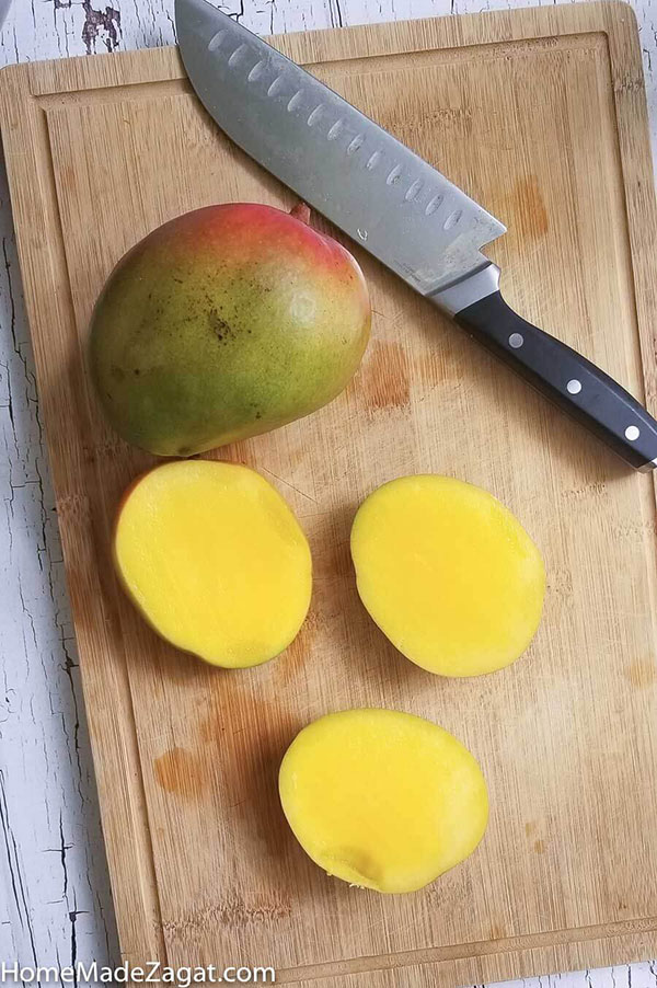 Mangoes sliced on a cutting board prior to removing the pulp from the skin.