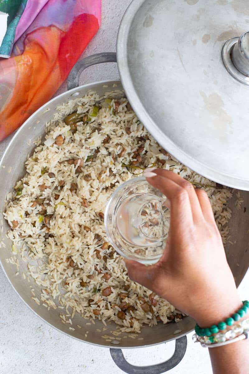 Adding coconut oil to pigeon peas and rice to add additional flavor.