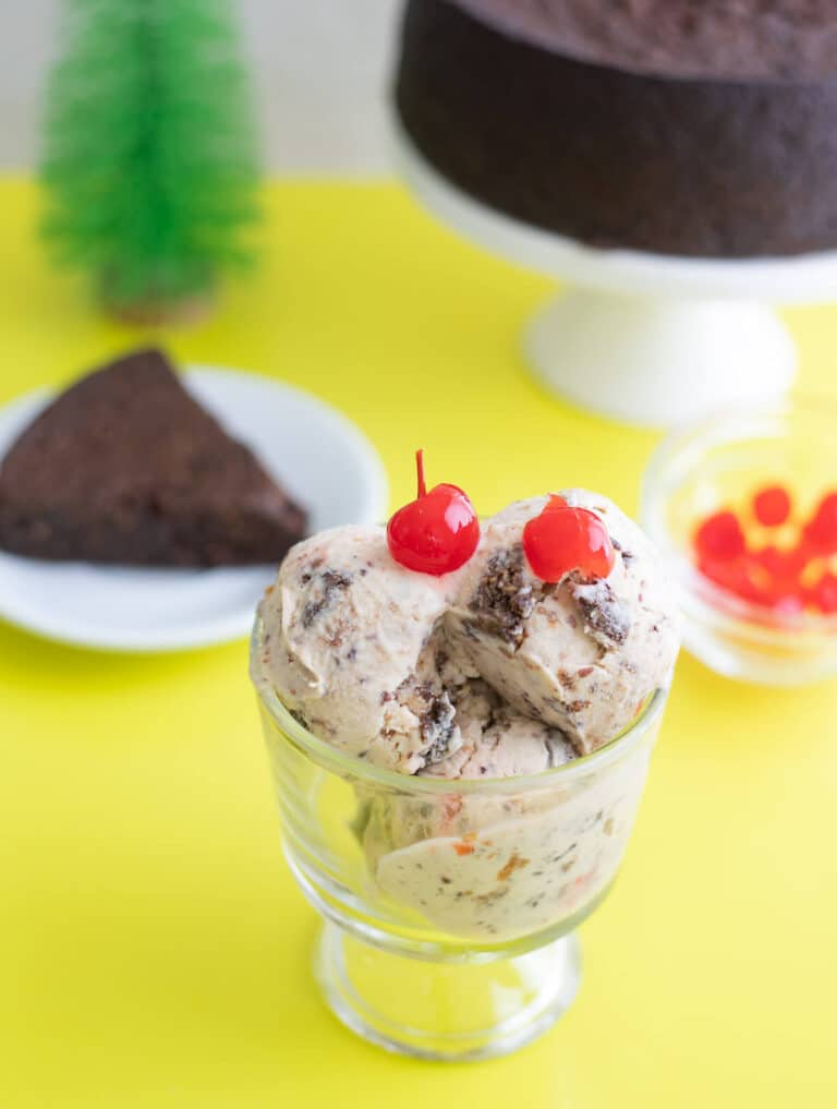 Black Cake Ice Cream scoops topped with red cherries in glass