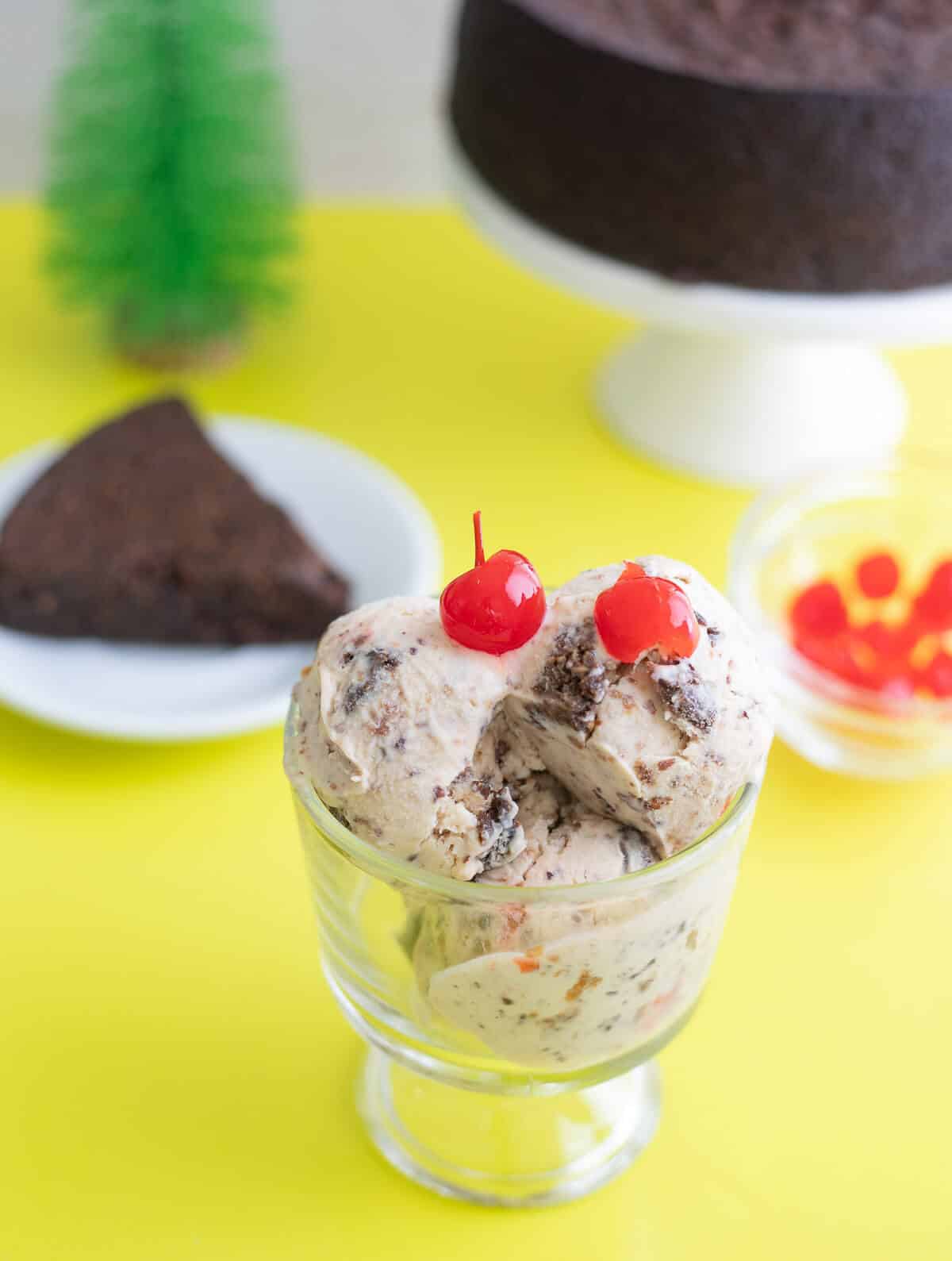 Black Cake Ice Cream scoops topped with red cherries in glass.