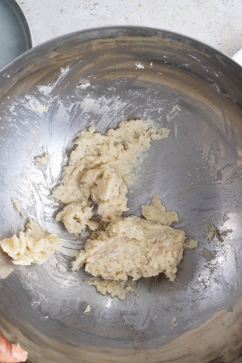 Mashed green bananas mixed with milk and butter in a bowl.