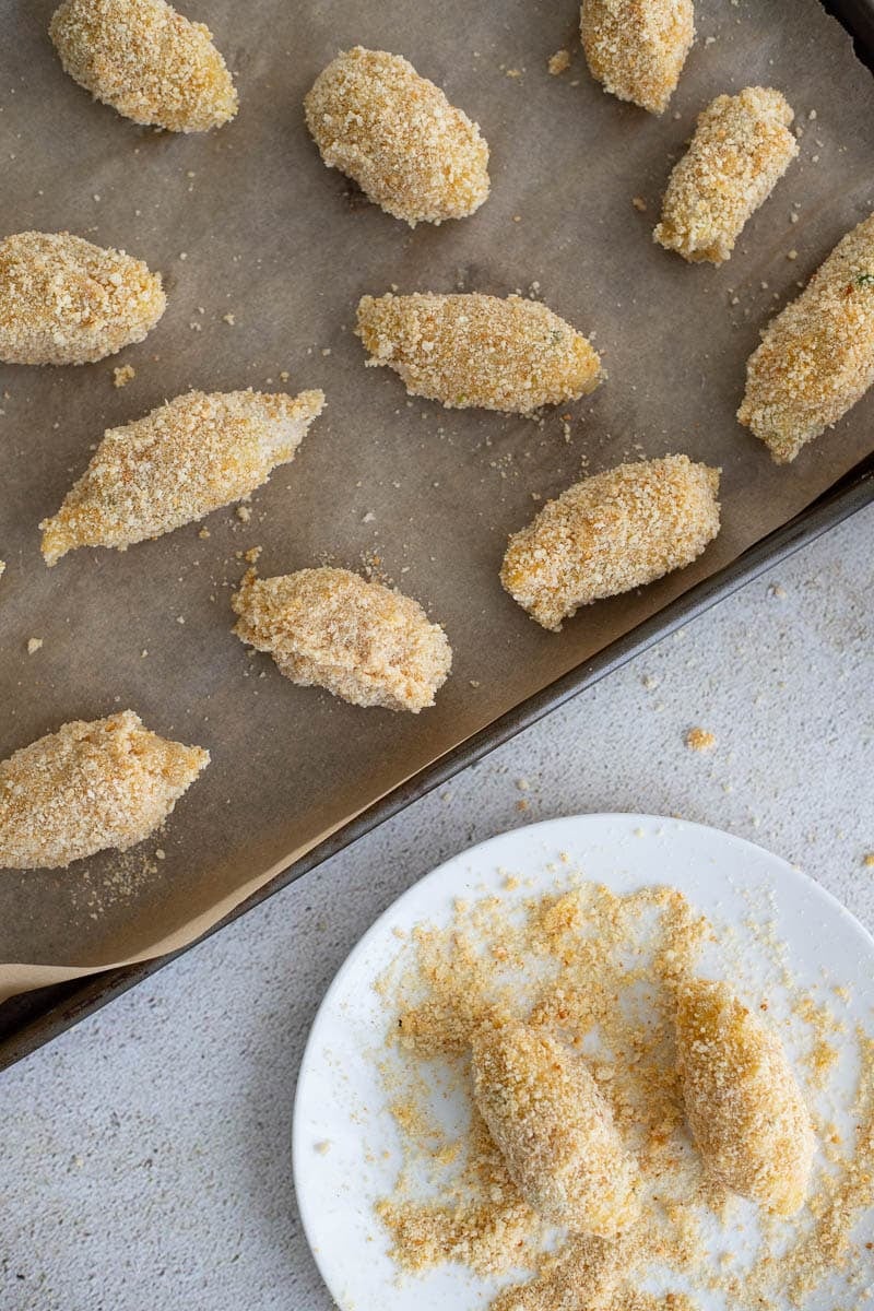Uncooked balls coated with breadcrumbs on a baking tray.