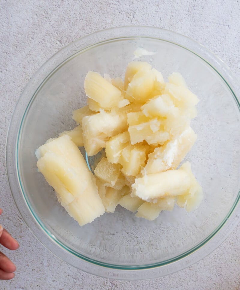 Boiled cassava pieces in a glass bowl after cooking until tender, ready to mash.