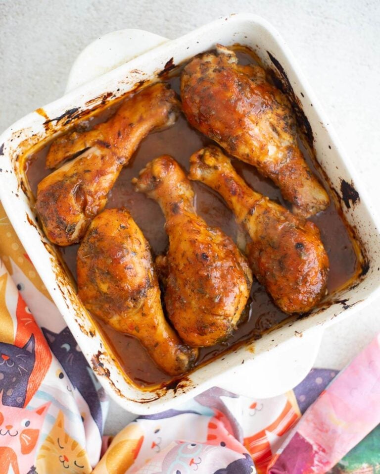 Trinidad-style baked chicken finished with BBQ glaze in a white baking dish.