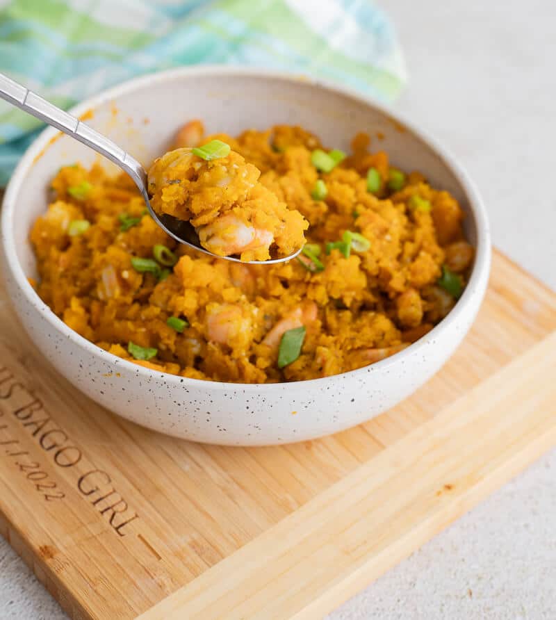 Close-up of spoonful of pumpkin with shrimp held over a bowl.