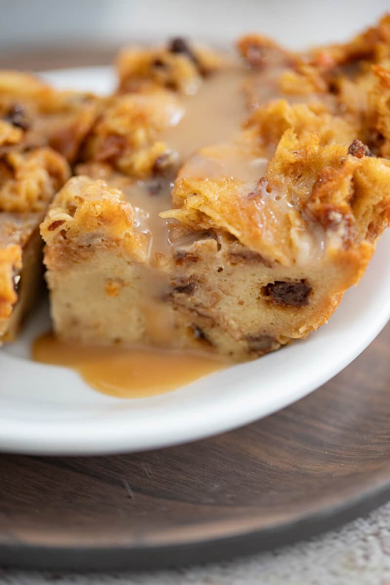 Close-up of a slice of ponche de crème bread pudding showing rich, custardy texture with raisins and cherries.