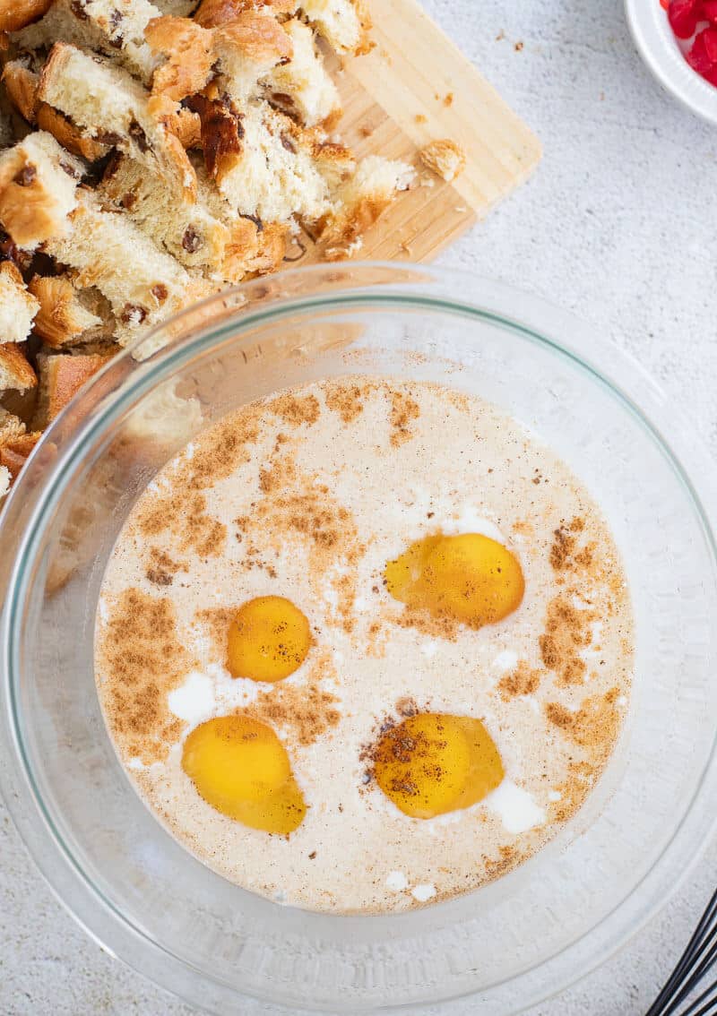 Bowl with eggs, milk, ponche de crème, and spices being mixed to make the custard for bread pudding.