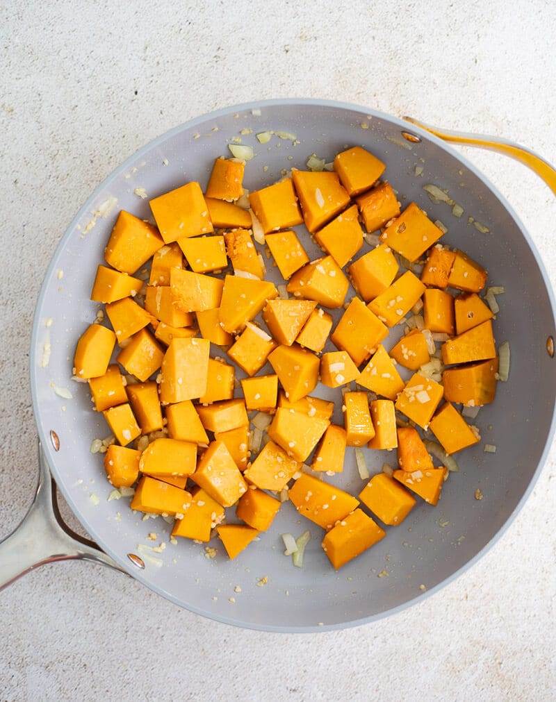 Cubed Caribbean pumpkin added to pan with sautéed garlic and onion for pumpkin shrimp recipe.