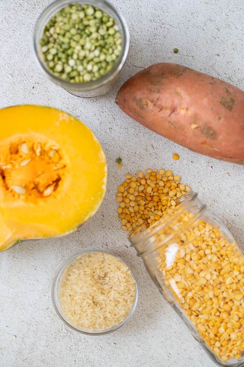 Grains and peas used in Caribbean cooking including rice, yellow split peas, green split peas, pumpkin, and sweet potato arranged on a counter
