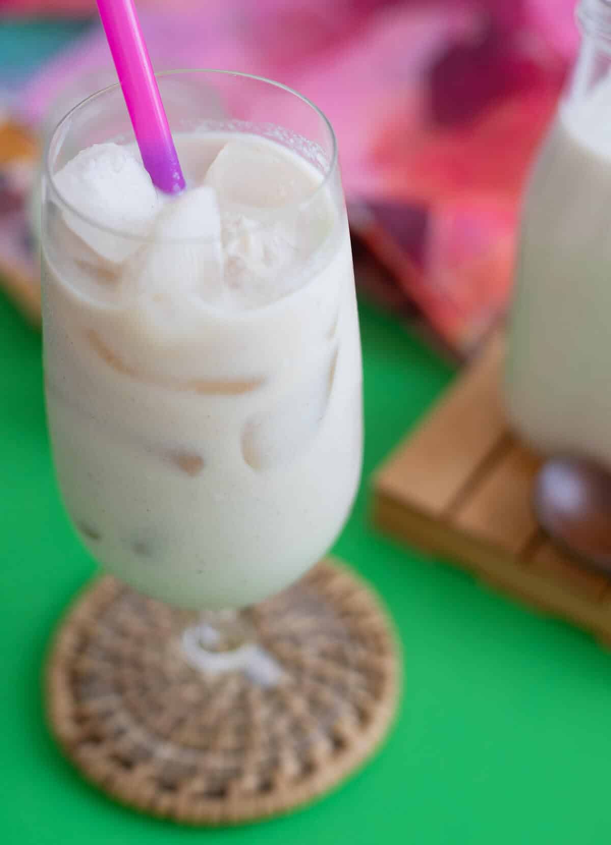 A cold glass of creamy Tobago dasheen punch filled with ice and served with a colorful straw.