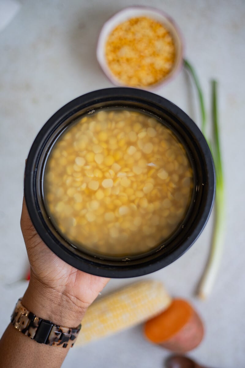Hand holding a bowl of soaked yellow split peas