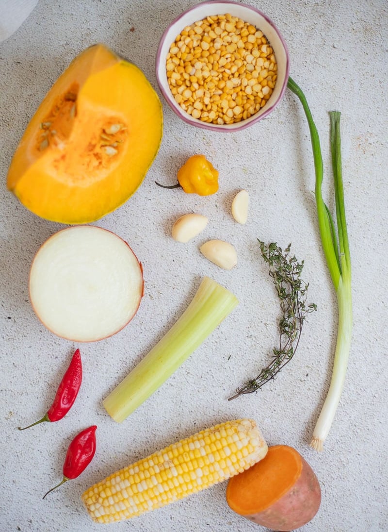 Ingredients for Caribbean pumpkin soup. Pumpkin, yellow split peas, peppers, garlic, celery, thyme, corn, onion, and scallion.