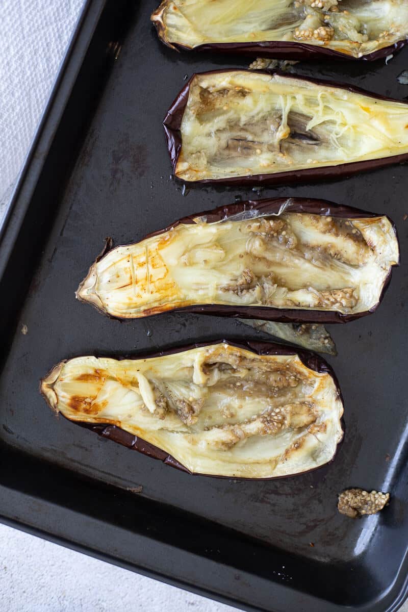 Roasted eggplant halves with flesh scooped out, ready to be filled.