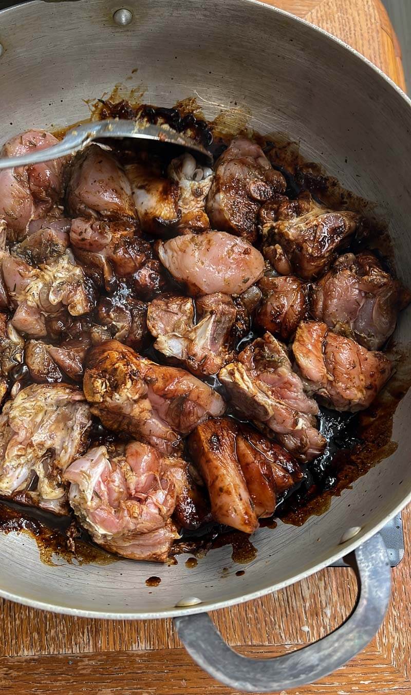 Seasoned meat added to caramelized sugar in a pot to stop the browning process for Trini stew.