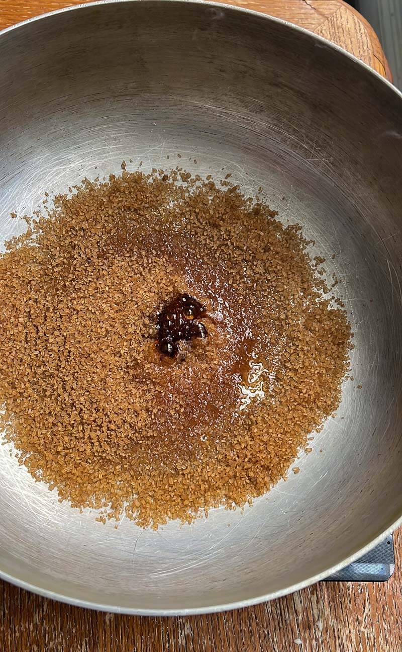 Sugar starting to melt in a pot, showing the early stage of browning for stewing.