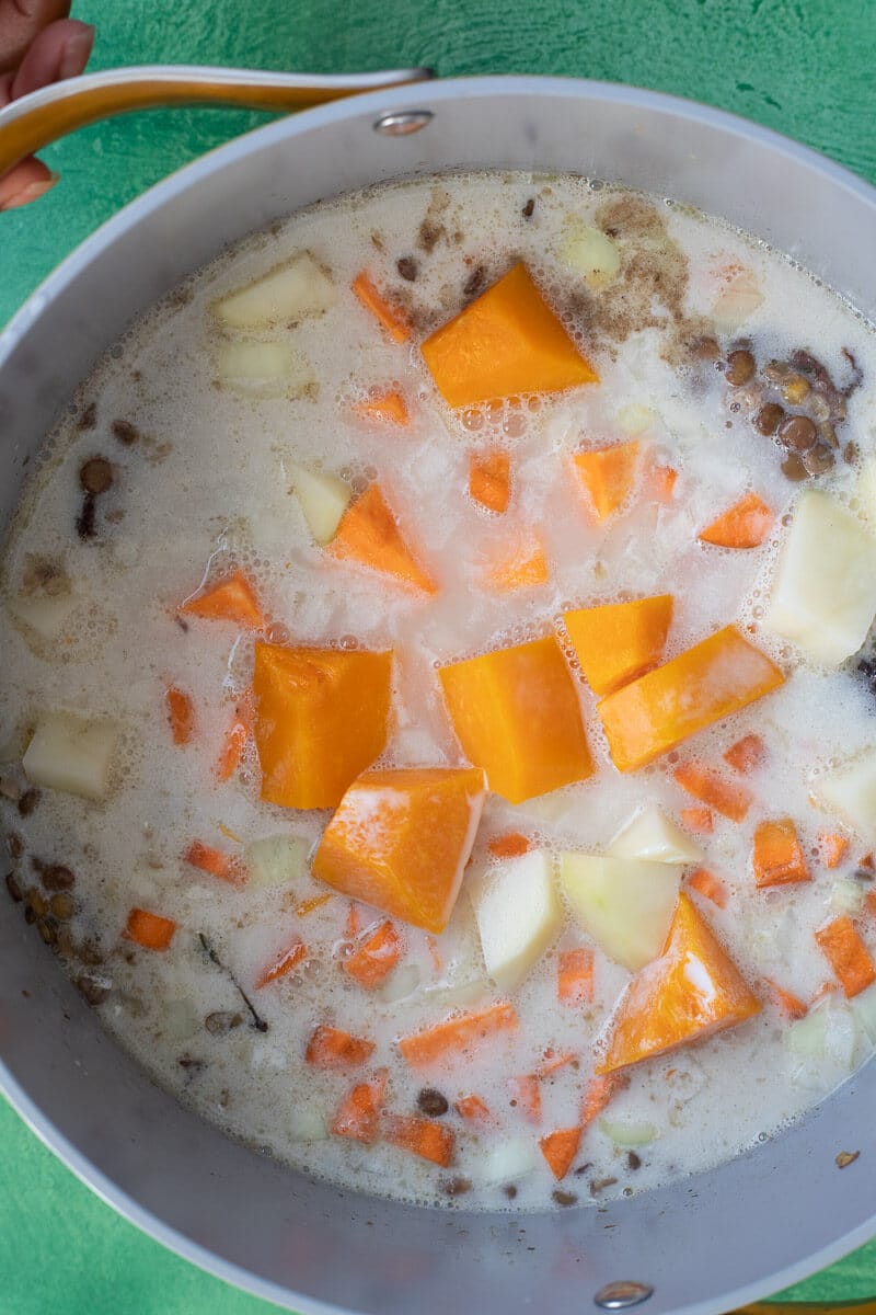 Caribbean lentil soup with pumpkin, potatoes, and coconut milk simmering in a pot
