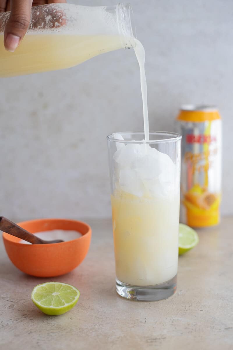 Pouring a homemade cassava drink over ice for a light and refreshing Caribbean beverage