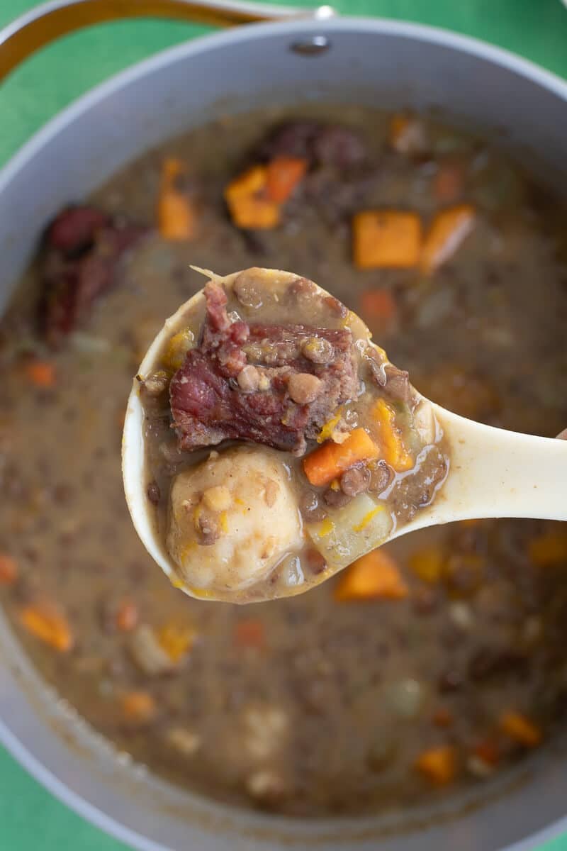 Spoonful of lentil soup with dumpling, pumpkin, and salted meat