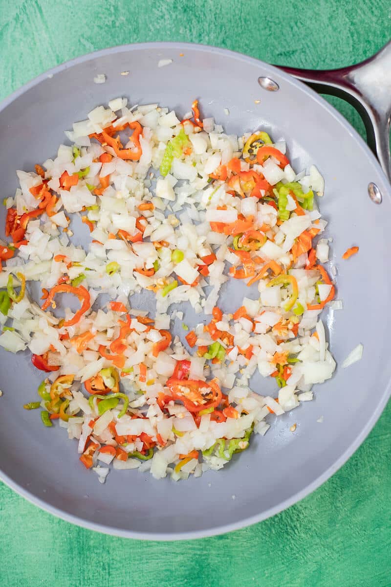 onion garlic and pimento peppers cooking in pan