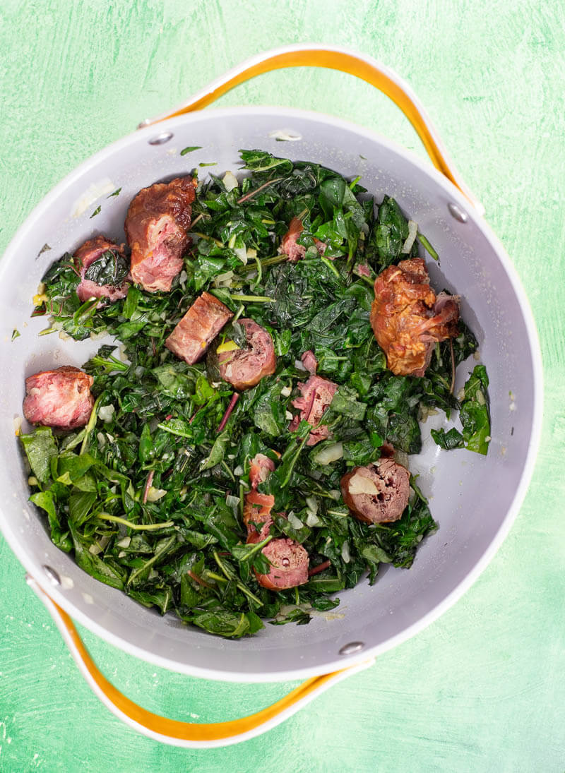 Bhaji cooking with smoked meat pieces in a pot
