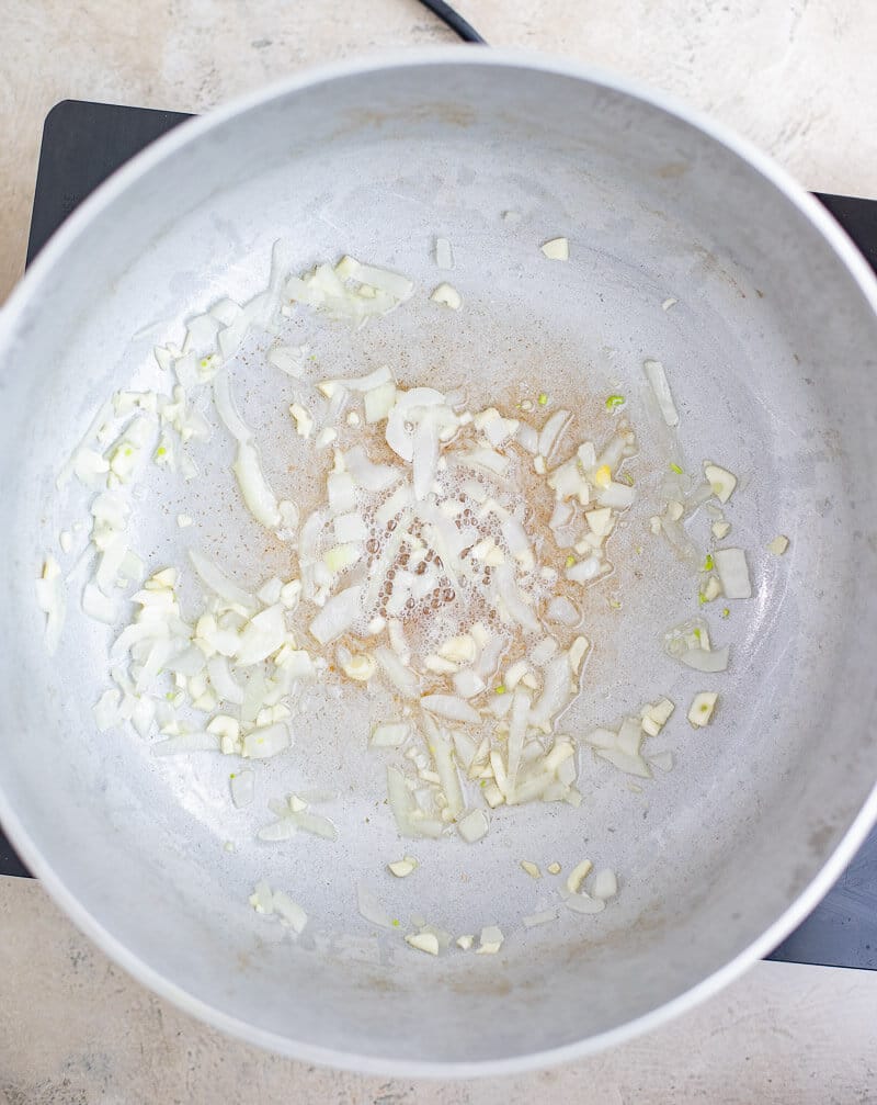 Chopped onion and garlic cooking in oil to begin the curry base.