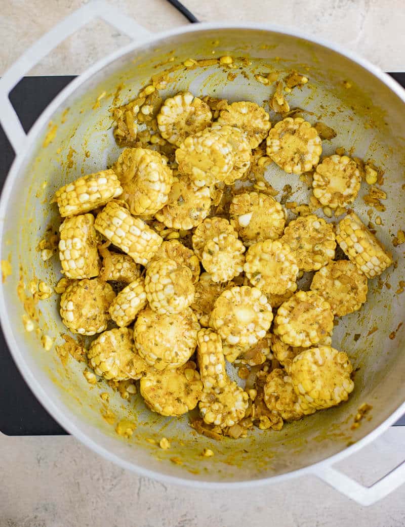 Corn rounds coated in the cooked curry mixture before adding the liquid.