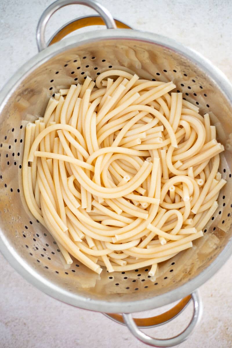Cooked macaroni draining in a metal colander