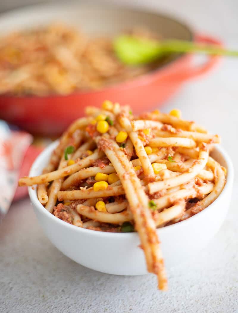 Caribbean-style macaroni and corned beef with corn and scallions served in a bowl