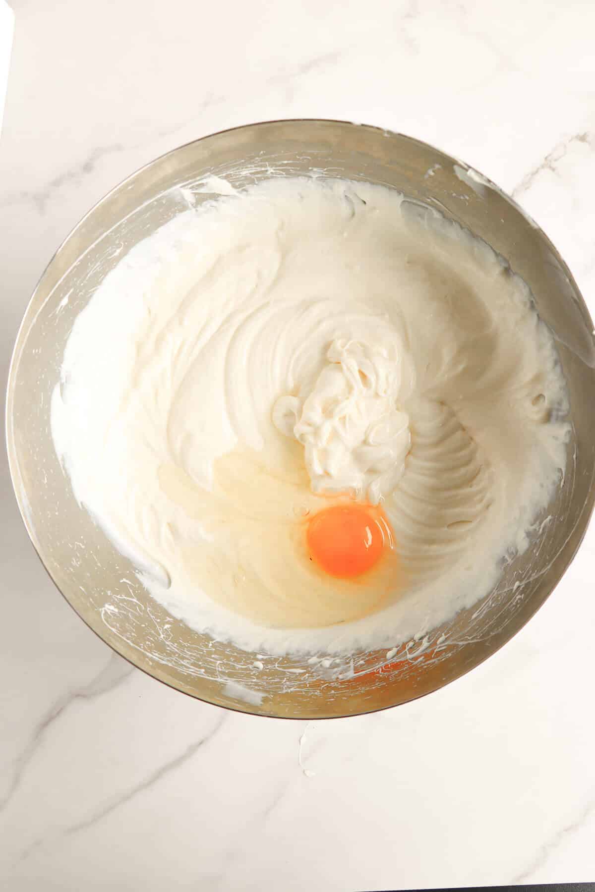 Adding an egg to the ponche de crème cheesecake filling.