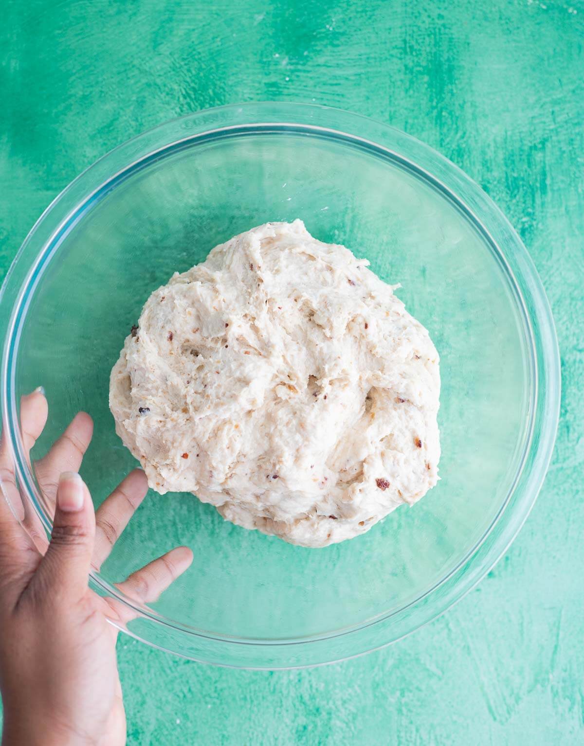Black cake cinnamon roll dough with pieces of soaked fruit mixed throughout