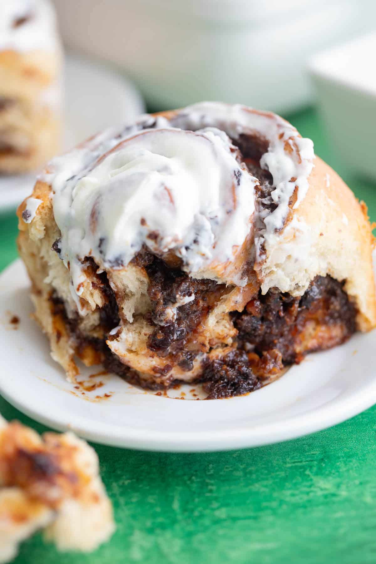 Black cake cinnamon roll filled with Caribbean rum-soaked fruits and topped with vanilla butter frosting