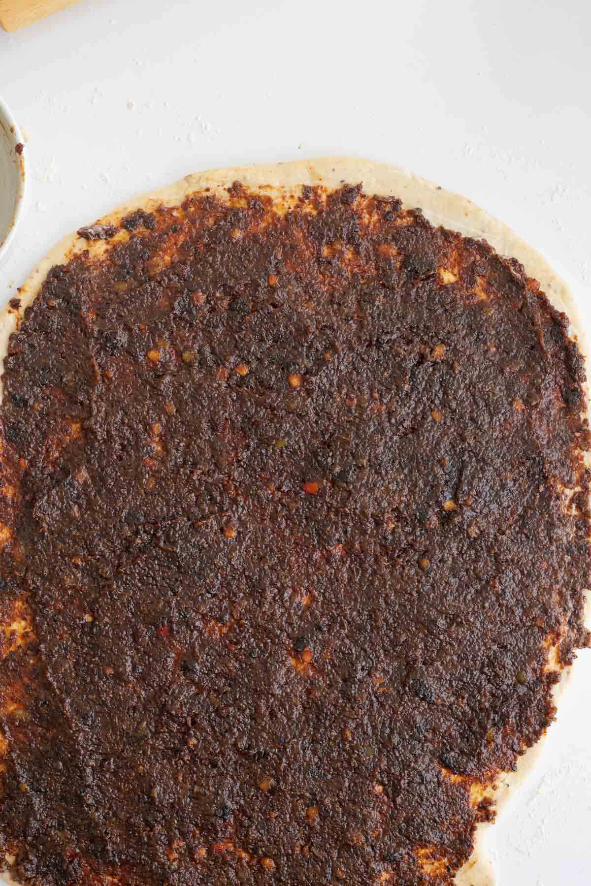 Soaked black cake fruit filling spread evenly over cinnamon roll dough
