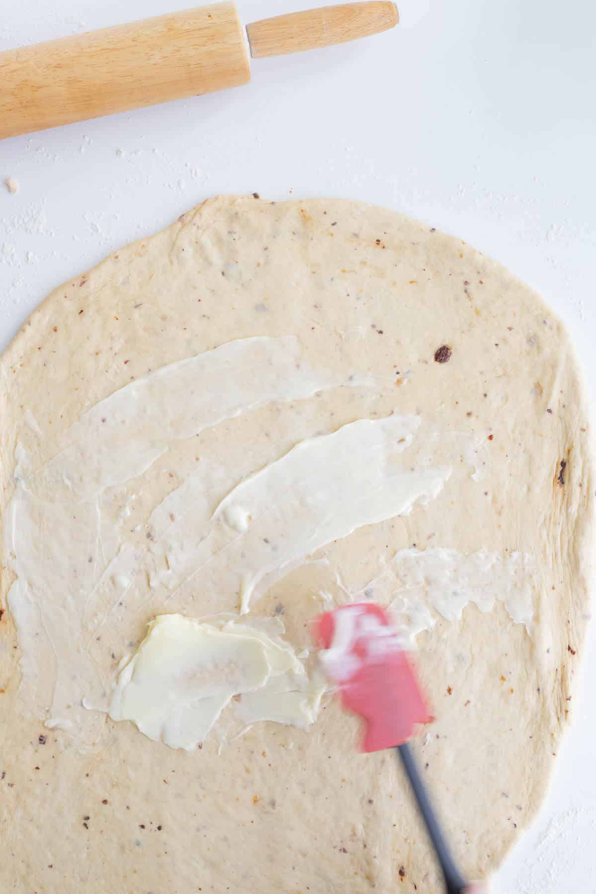 Softened butter spread over rolled cinnamon roll dough